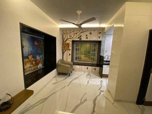 A hallway with a ceiling fan, a painting, a chair, and a window with a view of a garden.