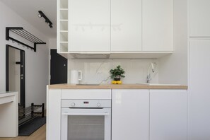 A modern kitchen with white cabinetry, a built-in oven, and a marble backsplash. - Functional Studio near Pole Mokotowskie Workspace Smart TV (Warszawa)