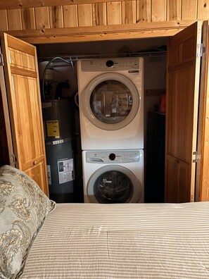 A laundry room with a washing machine and dryer, a refrigerator, and wooden cabinets. - No-Ferry Camano Log Cabin w/ Puget Sound Views, Beach Access & EV Charger (Camano)