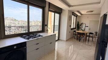 A modern kitchen with a built-in washer, large windows, and a dining area with a view of the city.