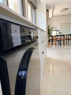 Eine moderne Küche mit einem Samsung Gerät, einem Essbereich mit Tisch und Stühlen sowie einer Topfpflanze.