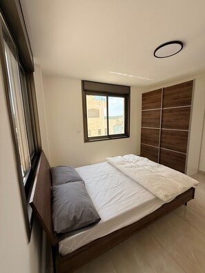 A bedroom with a bed, a window, and a wardrobe. - 3-bedroom apartment in beautiful Masyon in Ramallah (Ramallah)