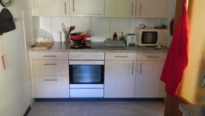 Een compacte keuken met witte kastjes, een ingebouwde oven, een magnetron en een broodrooster.