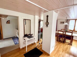 Ein Zimmer mit Holzboden, weißen Wänden, einem weißen Schreibtisch mit Stuhl, einem Spiegel und einer Wanduhr.