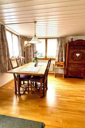 A dining area with a wooden table, chairs, a hanging lamp, and a dresser with a heart-shaped decoration. - Stähli-Huus by Interhome (Interlaken)