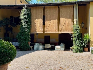 A courtyard with a seating area, a pergola, and potted plants. - Villa Leopardi - A luxury guesthouse in the Parma countryside (Emilia-Romagna)