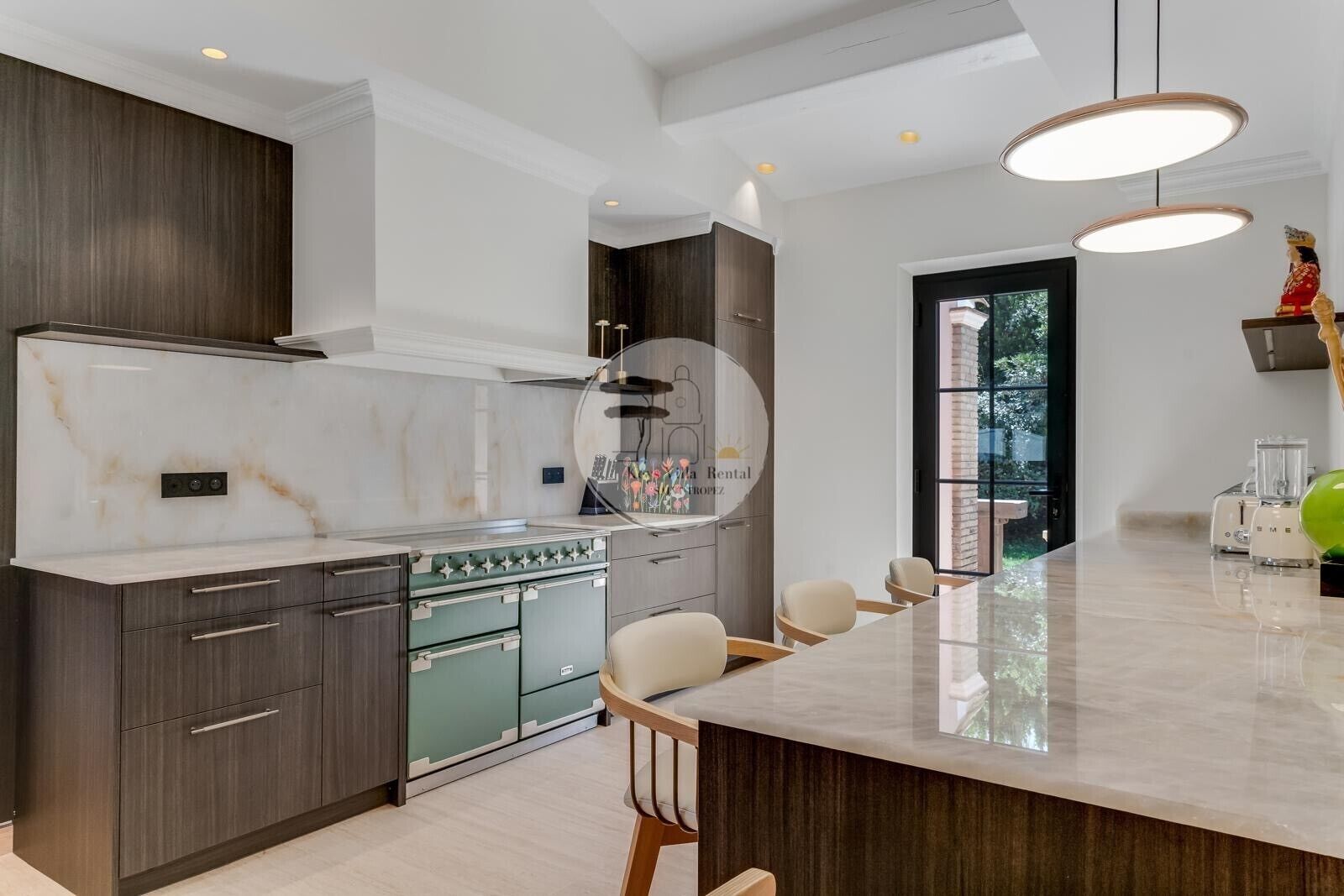 A modern kitchen with a central island, dark cabinetry, and a large window.