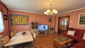 A living room with a dining table, sofa, TV, and decorative items. - Family home with a garden: Beach, mountains, and pets welcome (Garage included) (La Caridad)