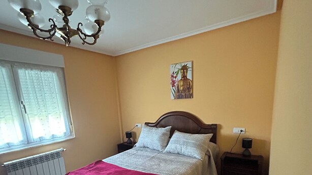 A bedroom with a bed, bedside tables, a nightstand, a radiator, a window with curtains, and a chandelier. - Family home with a garden: Beach, mountains, and pets welcome (Garage included) (La Caridad)