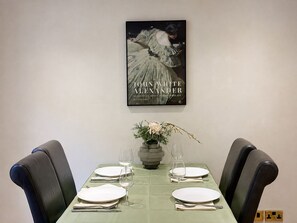Ein Esstisch für vier Personen, darüber ein gerahmtes Kunstwerk.