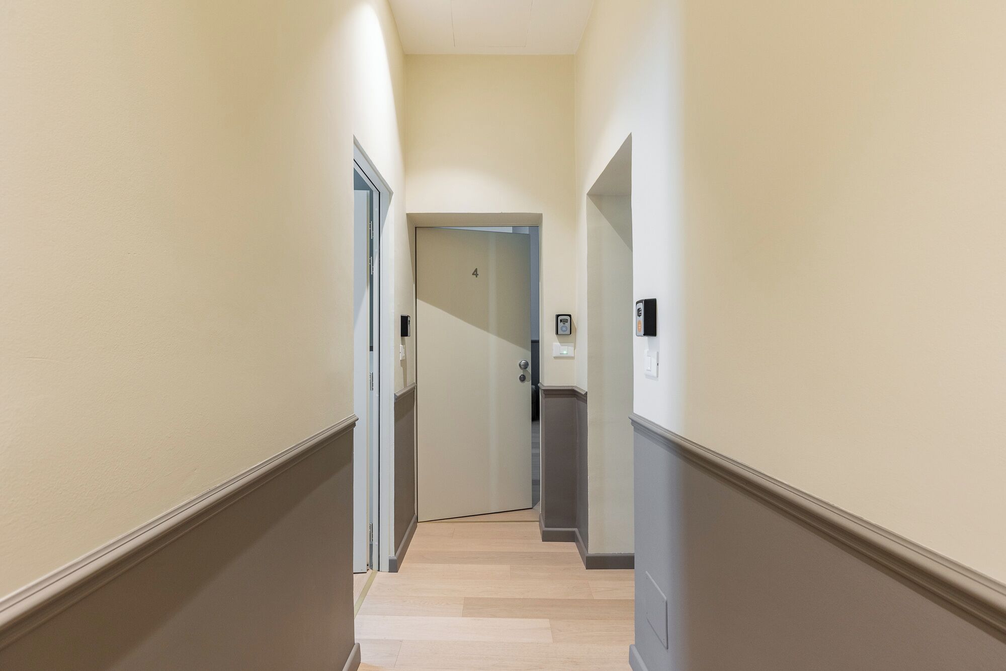 Un corridoio con porte su entrambi i lati, una porta contrassegnata col numero 4 e un interruttore sulla parete.
