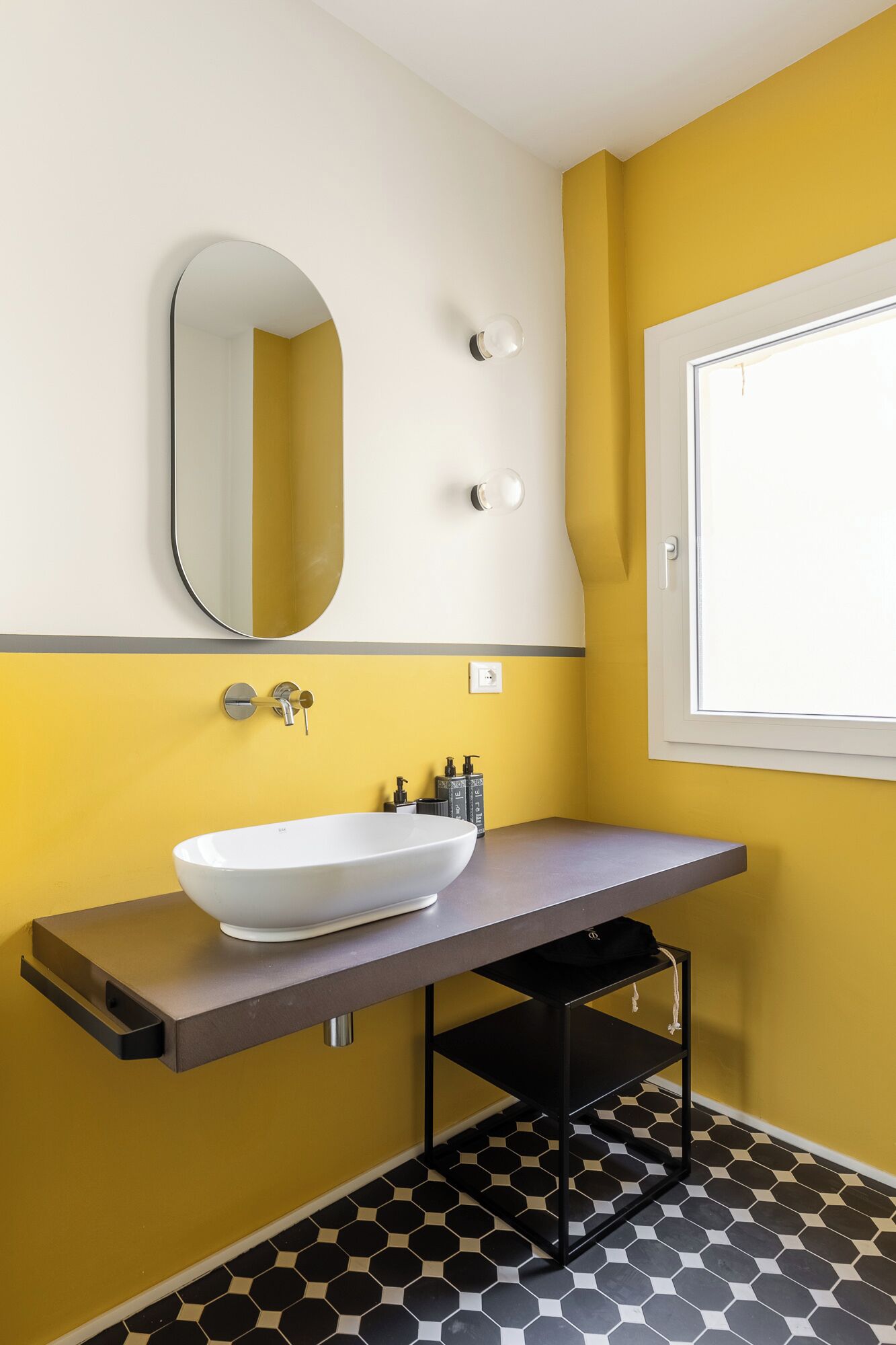 A bathroom with a white sink, a mirror, and a window.