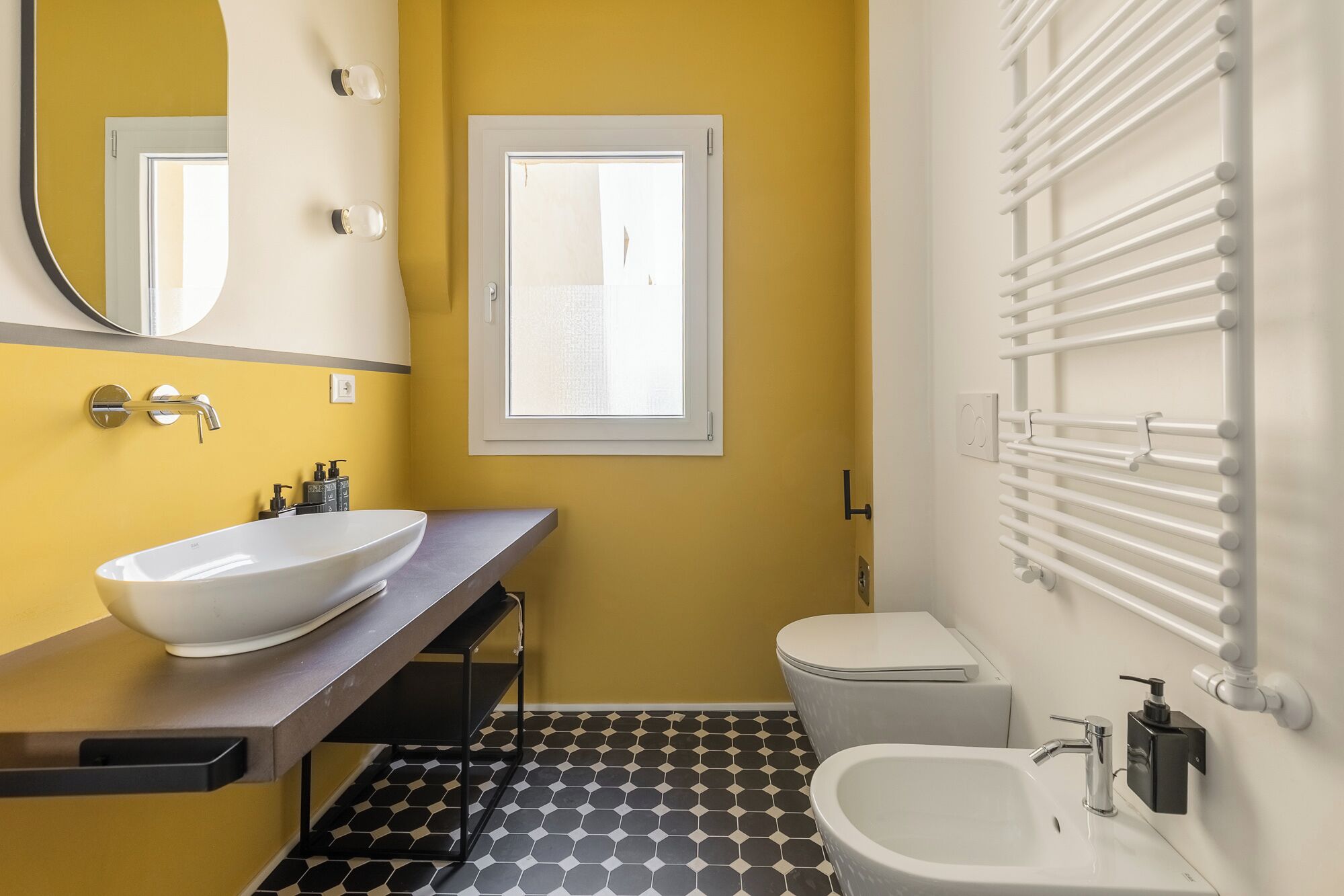 Une salle de bain avec un lavabo blanc, des toilettes et une fenêtre.