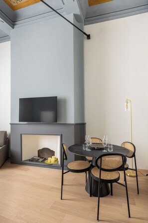 A modern living room with a fireplace, a flat-screen TV, and a round dining table with chairs.