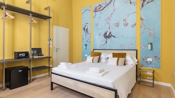 Une chambre d’hôtel équipée d’un lit, d’un coffre-fort, d’un minibar, d’un miroir et d’un mur orné d’un tableau représentant un singe.