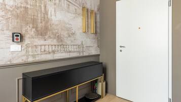 Une pièce avec un grand téléviseur noir posé sur un meuble doré, une porte blanche et un interrupteur fixé au mur.