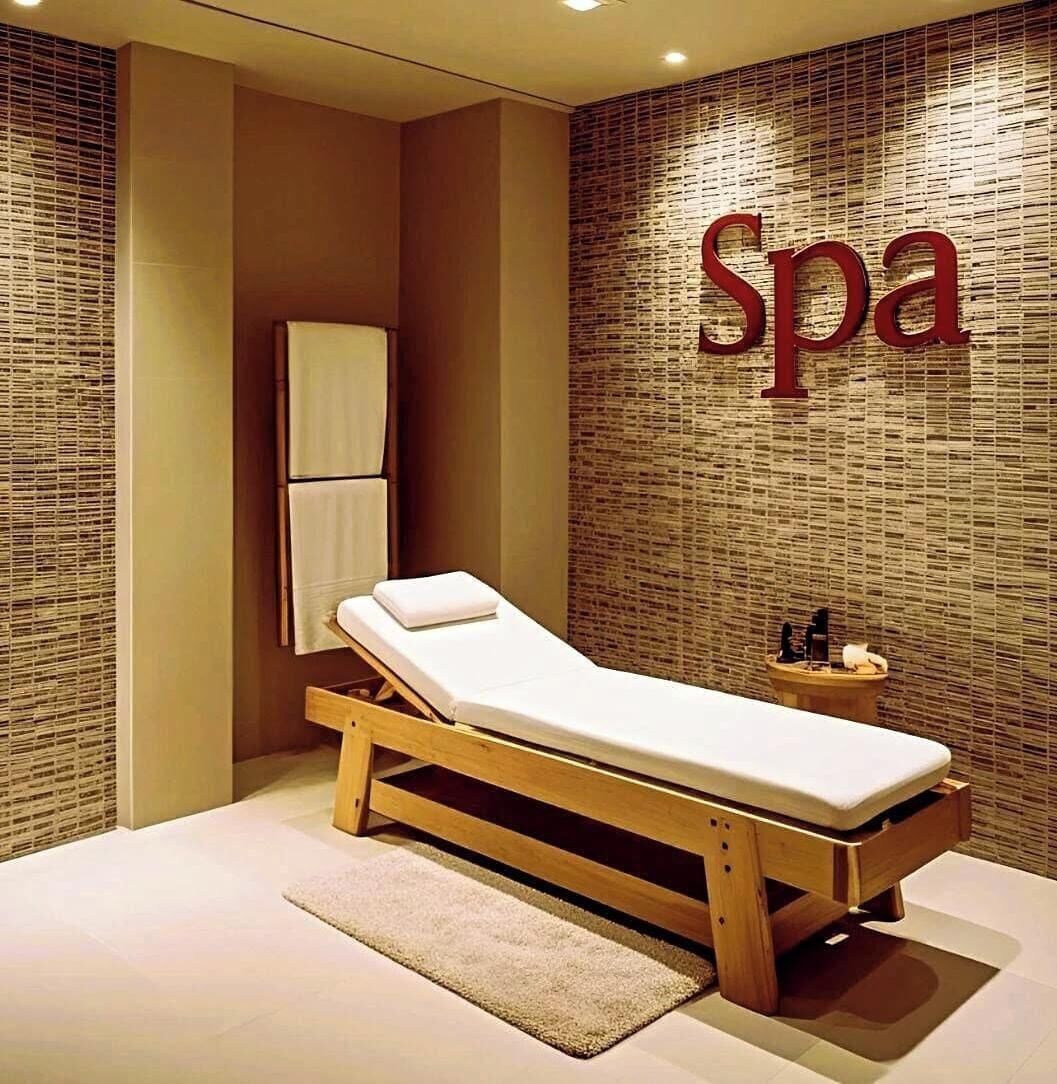 A spa room with a massage table, a towel rack, and a wall with the word 'Spa' in large letters.