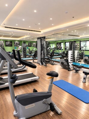 Ein Fitnessstudio mit Laufbändern, Kraftgeräten und Trainingsmatten.