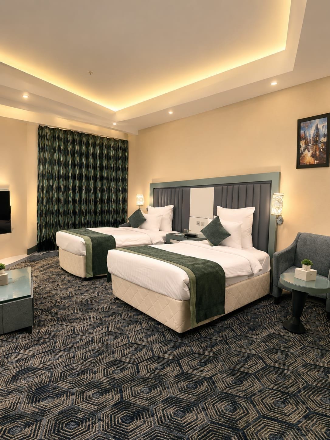 A hotel room with two beds, a sofa, a small table, and a large window.