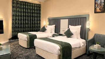 A hotel room with two beds, a sofa, a small table, and a large window.