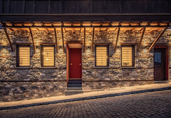 A stone building with a red door, wooden beams, and stone walls.