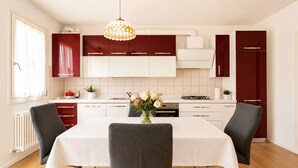 A modern kitchen with a dining table, chairs, and a vase of flowers. - Garden view in the heart of Prosecco Hills (San Vendemiano)