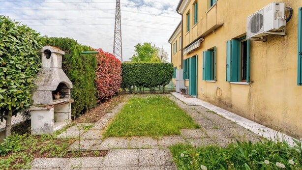 A courtyard with a stone bench, a hedge, and a building with green shutters. - Garden view in the heart of Prosecco Hills (San Vendemiano)