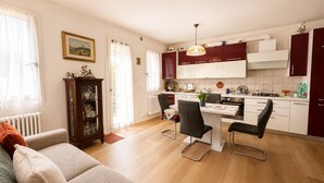 A modern kitchen with white cabinets, a dining table with chairs, and a radiator. - Garden view in the heart of Prosecco Hills (San Vendemiano)