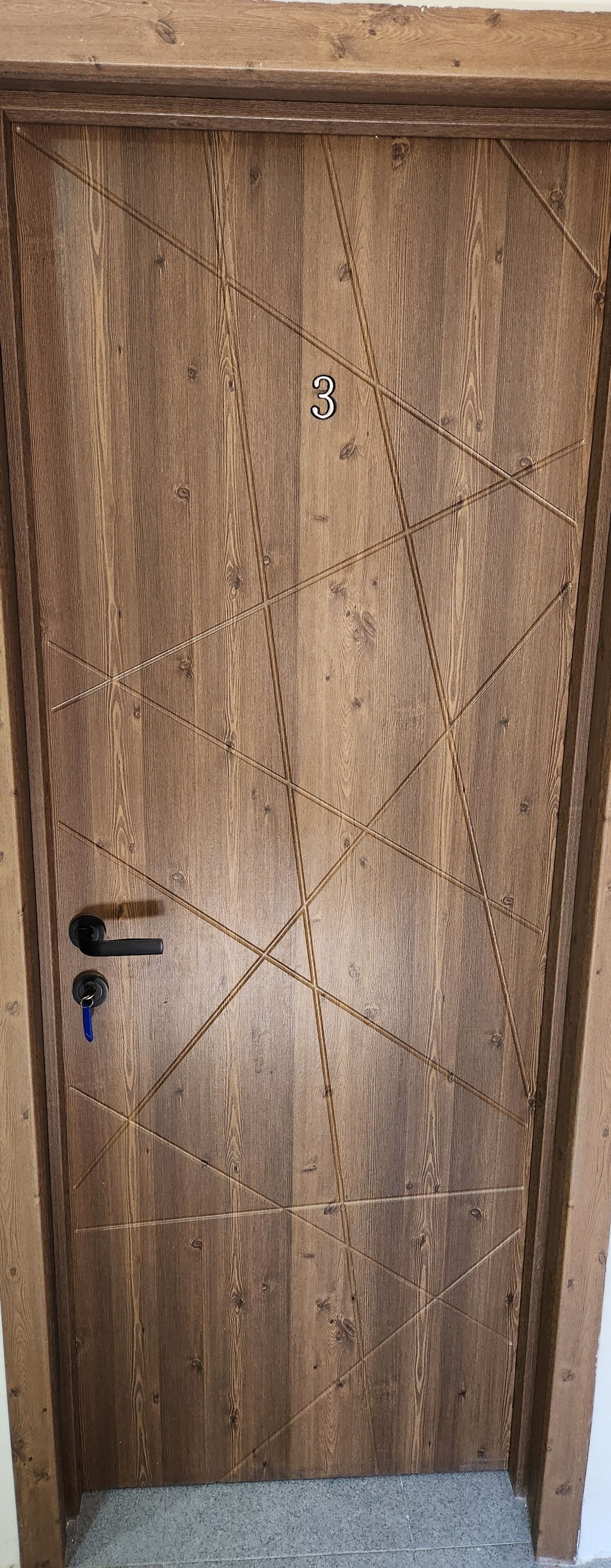 A wooden door with a geometric pattern and a keyhole.