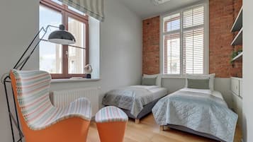 A room with two beds, a chair, a radiator, and a window with blinds.