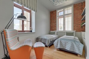 Una habitación con dos camas, una silla, un radiador y una ventana con persianas.