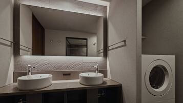 A modern bathroom with two sinks, a large mirror, and a built-in washing machine.