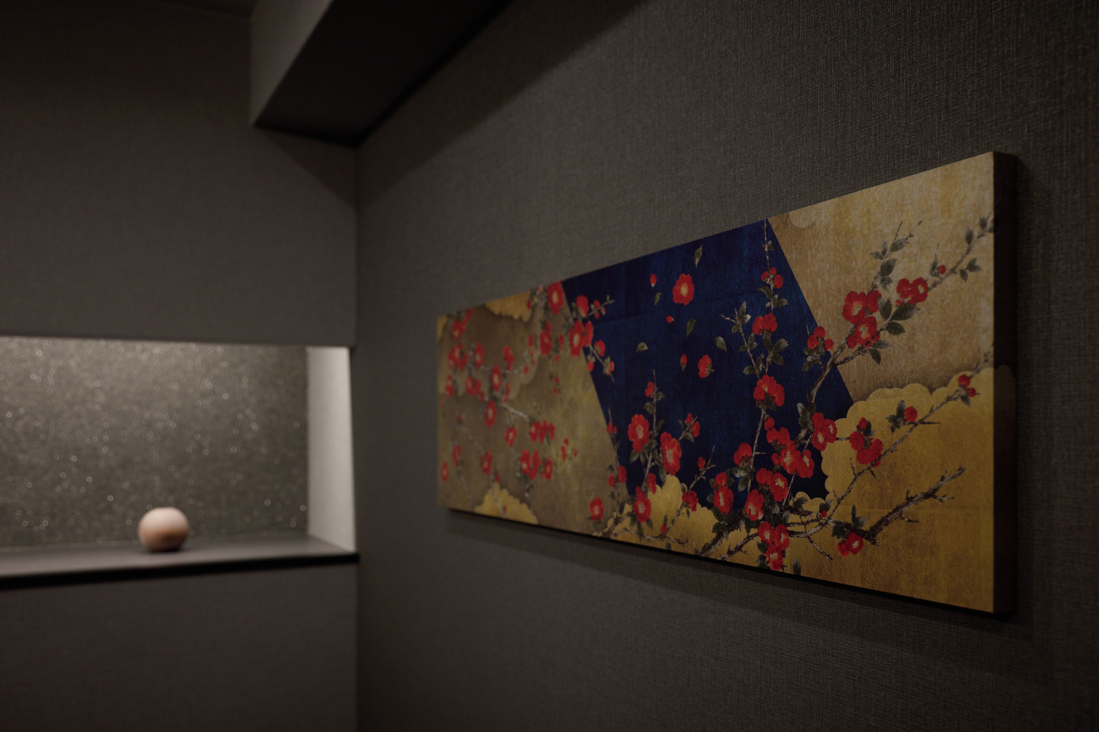 Ein Zimmer mit einer dunkel strukturierten Wand und einem einzelnen gerahmten Kunstwerk, das rote Blumen zeigt.