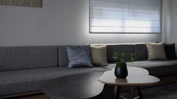 A modern living room with a grey sofa, a round coffee table, and a potted plant.