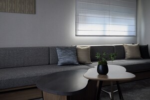 A modern living room with a grey sofa, a round coffee table, and a potted plant.