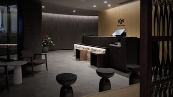 A reception area with a reception desk, seating, and a wall with a logo.