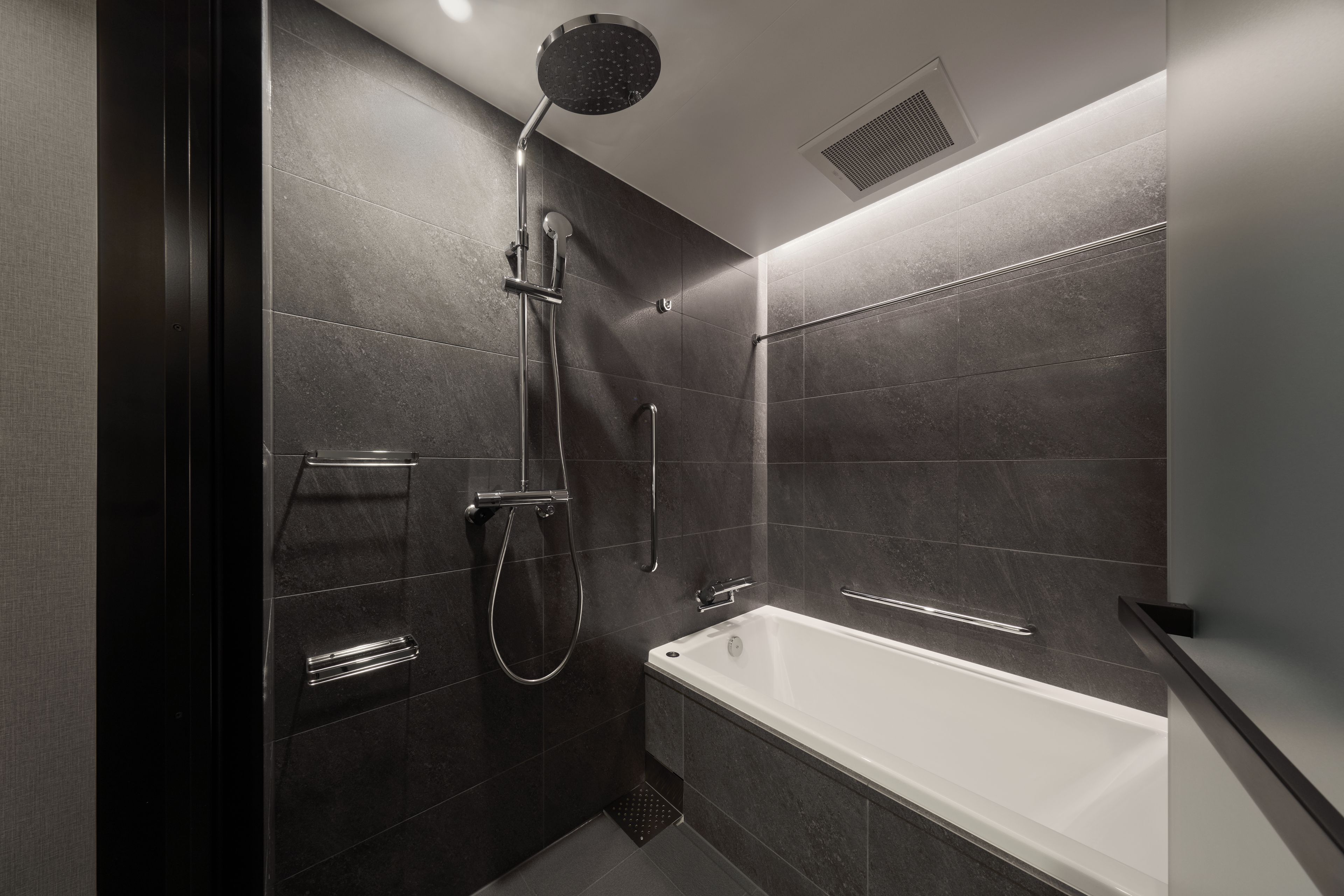 Une salle de bain moderne équipée d’une baignoire, d’une douche avec un pommeau de douche amovible et d’un porte-serviettes.