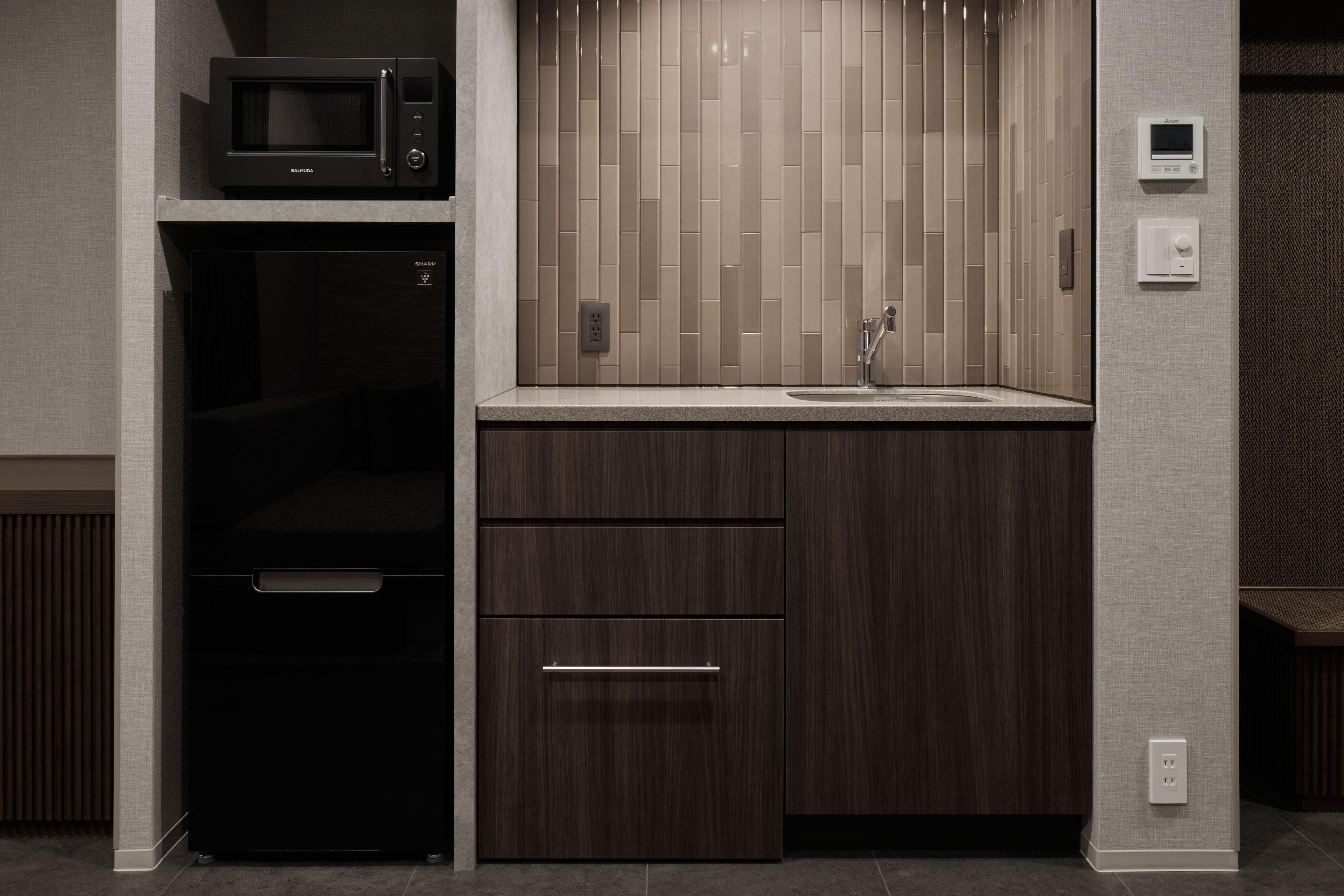 A compact kitchen with a microwave, a sink, and a wooden cabinet.