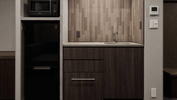 A compact kitchen with a microwave, a sink, and a wooden cabinet.