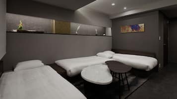 A modern hotel room with three beds, a small round table, and a painting on the wall.