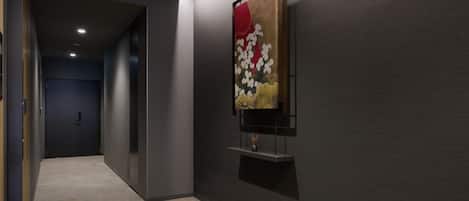 A hallway with a modern art piece on the wall, a door at the end, and a textured floor.