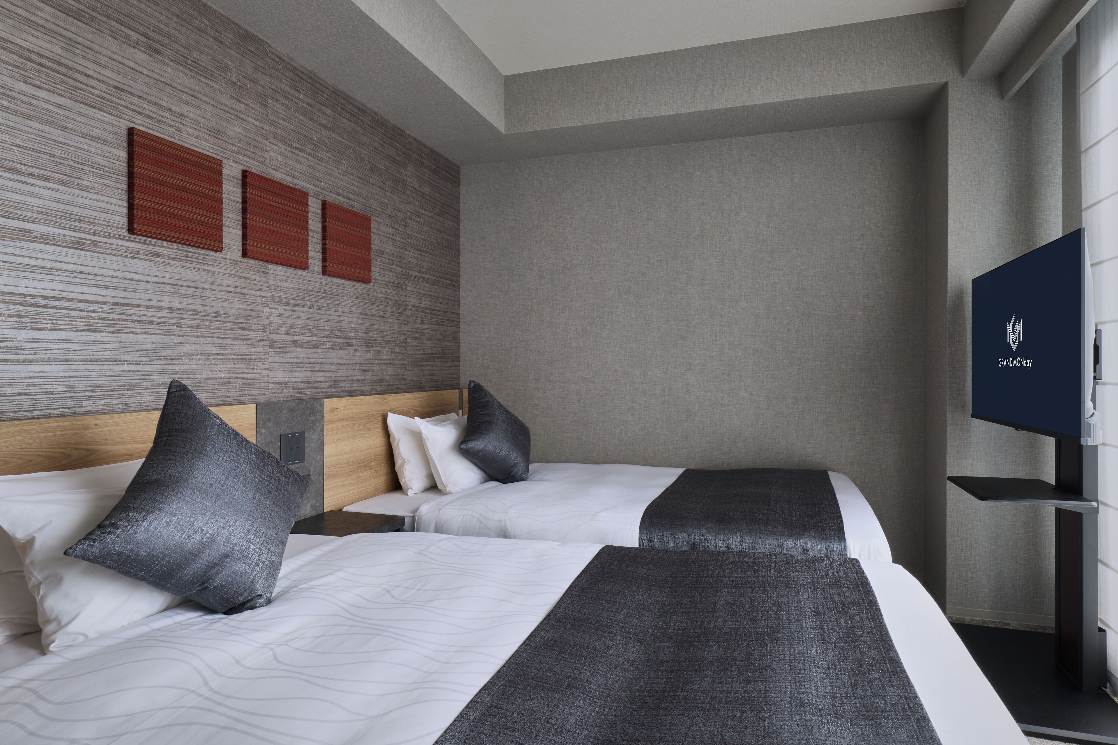 A hotel room with two beds, a flat-screen TV, and a textured wall.