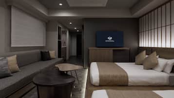 A modern hotel room with a sofa, a bed, a small table, and a TV on the wall.