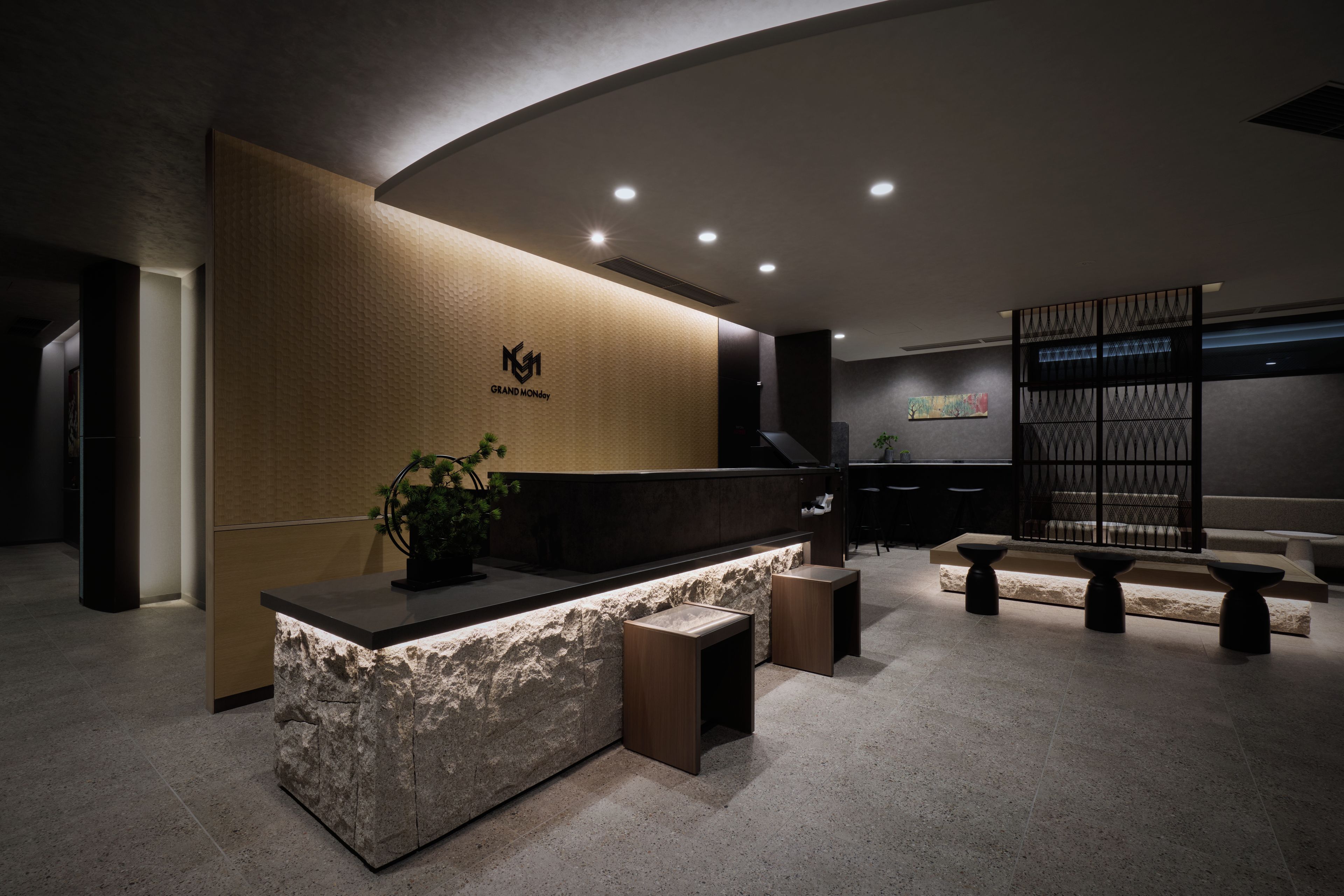 A reception desk with a logo, a plant, and a seating area with a partition.