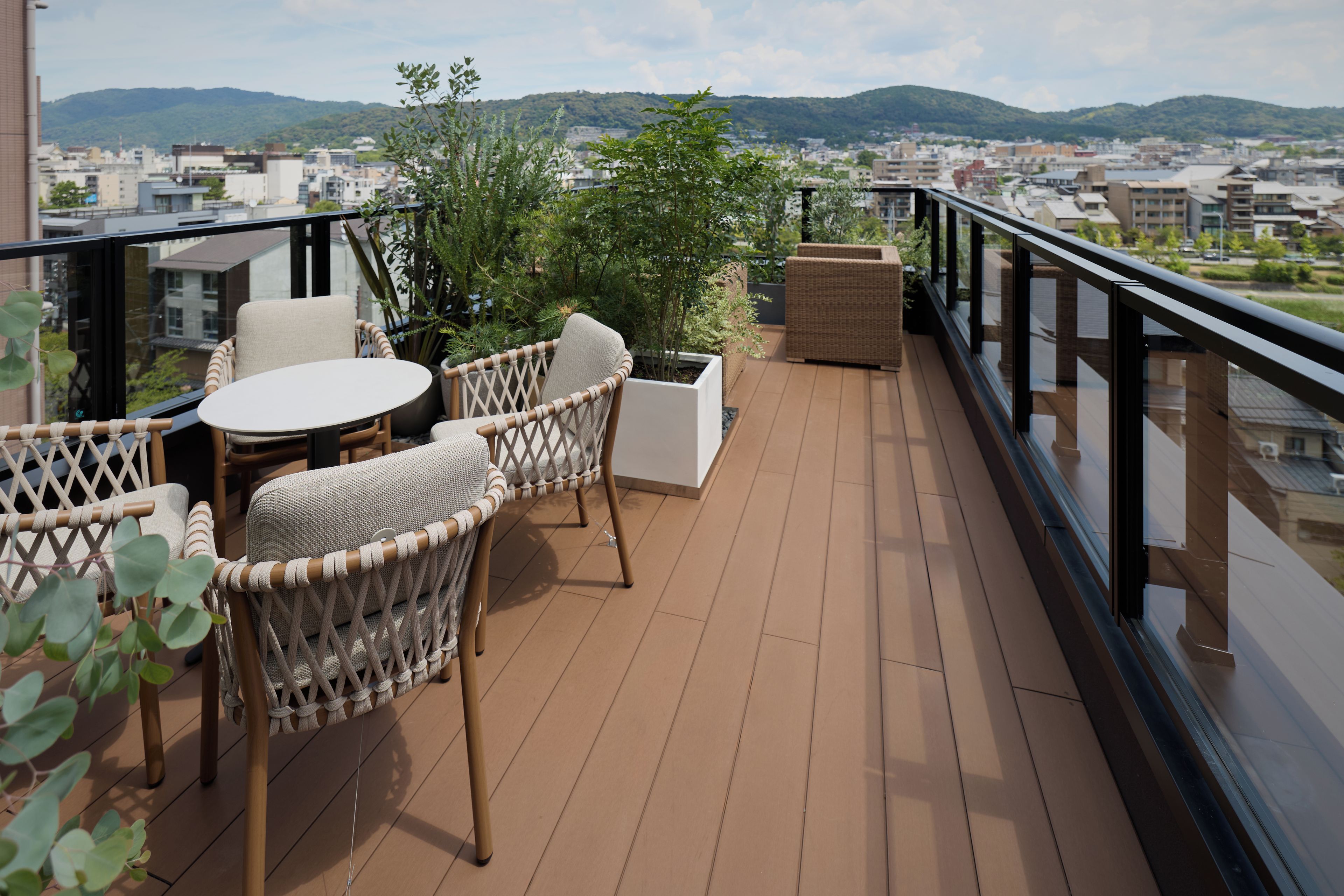 A balcony with wicker furniture, a round table, and potted plants.