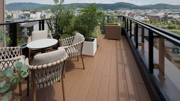 A balcony with wicker furniture, a round table, and potted plants.