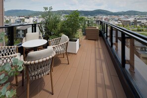 A balcony with wicker furniture, a round table, and potted plants. - GRAND MONday KYOTO SHIJO KAWARAMACHI (Kyoto)