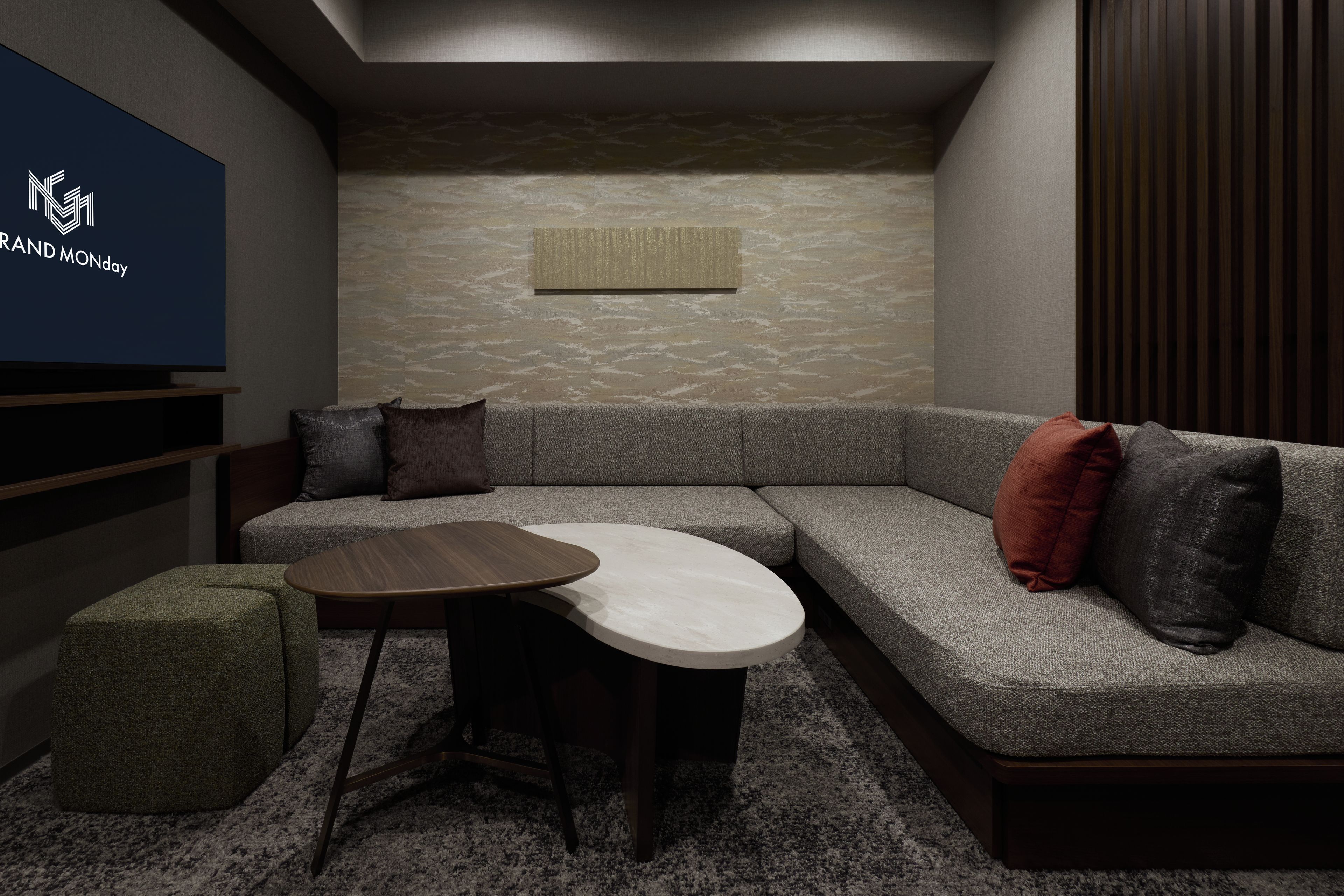 A modern living room with a sectional sofa, a round coffee table, and a small ottoman.