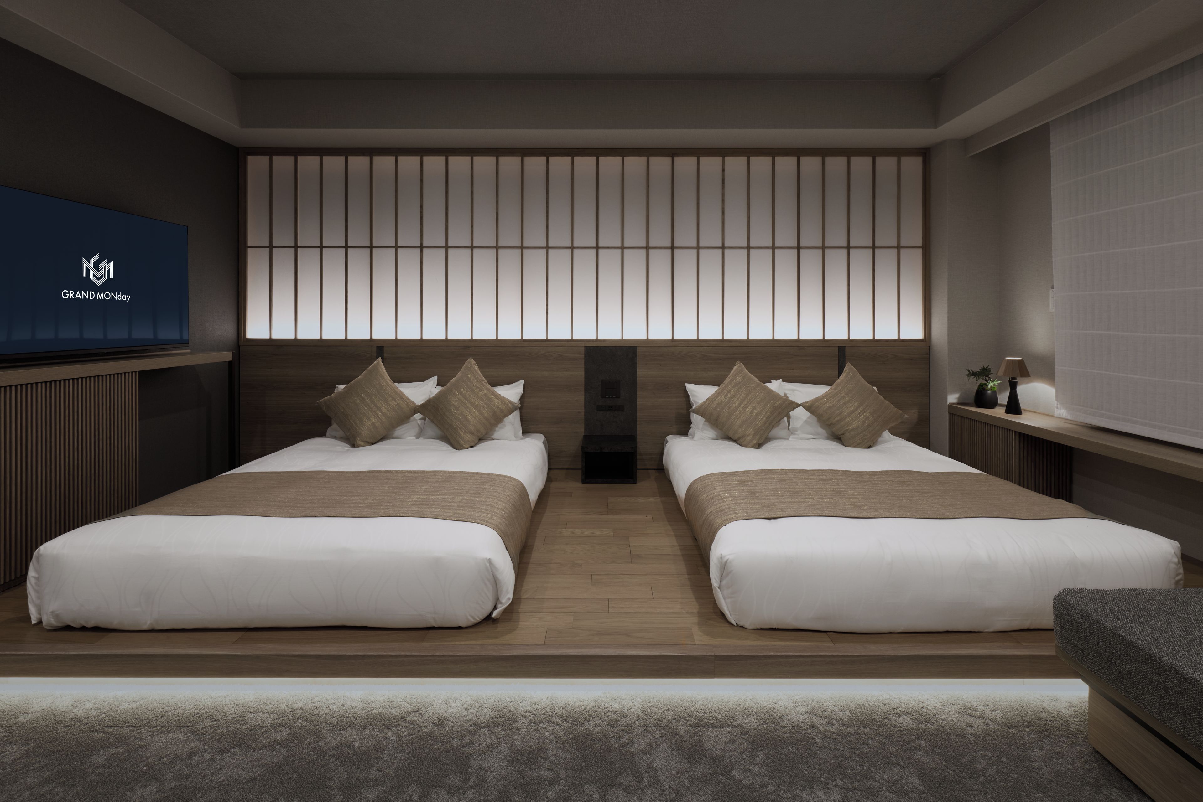 A modern hotel room with two beds, a large TV, and a sliding shoji screen.