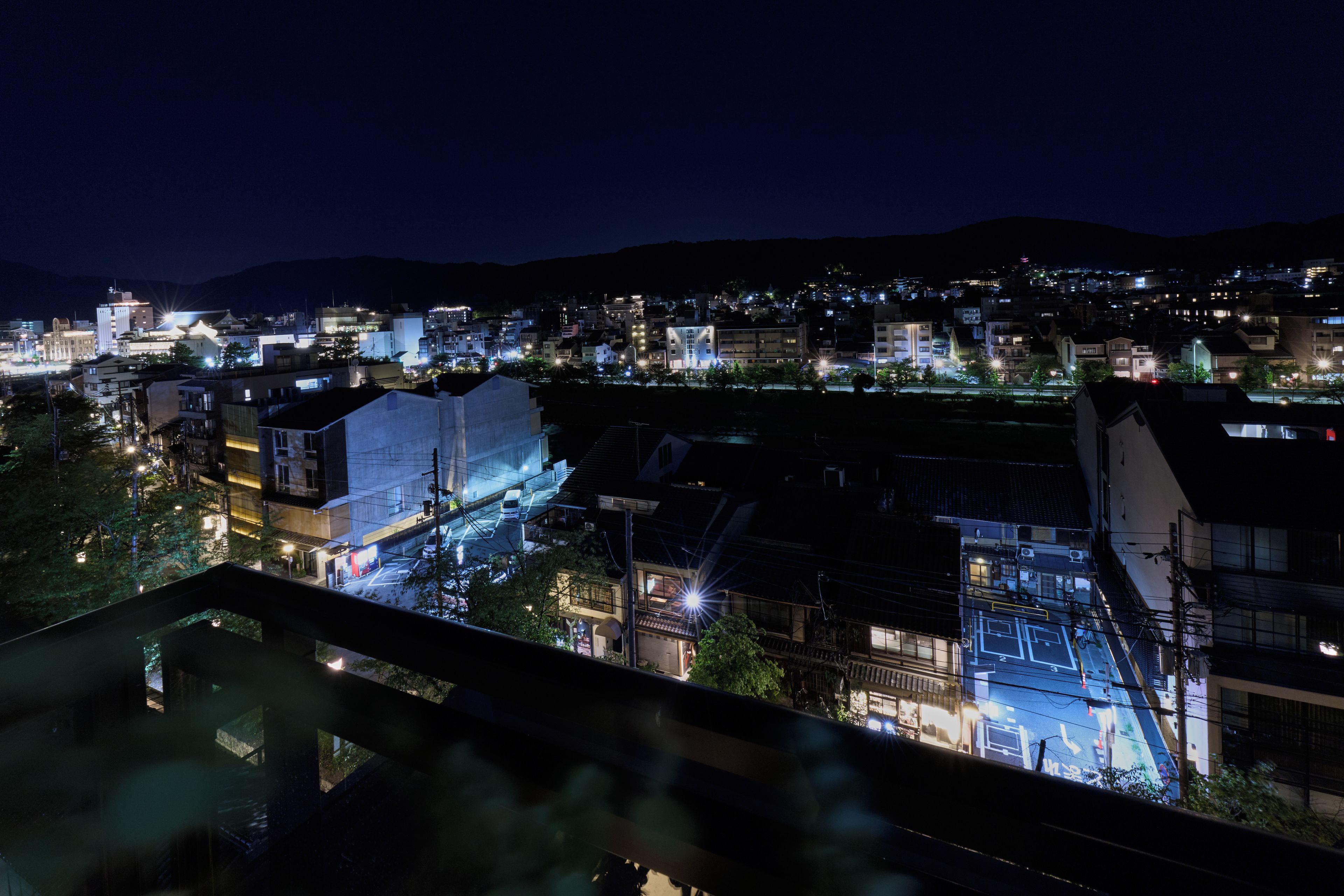A nighttime cityscape with illuminated buildings and a river.
